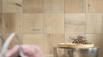 RAKO | Detail dlaždice v malém rozměru s imitací dřeva v béžové barvě, která je využitá jako obklad na stěnu.