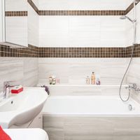 RAKO | Koupelna ve světle šedé barvě s imitací mramoru. Jako doplněk mozaika ze série Board s imitací dřeva v tmavě hnědé barvě.