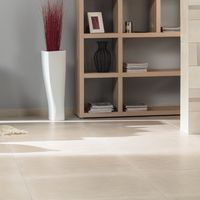 RAKO | Obývací pokoj s dlažbou ze série Rebel s imitací betonu v béžové barvě ve velkém formátu 80 x 80 cm a zeď z dekoru s pruhy.