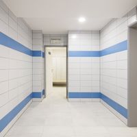 RAKO | Sociální zázemí bazénu Bratislava. Zdi obložené obklady ze série COLOR ONE, v bílé a modré barvě ve formátu 20 x 40 cm. Na zemi je dlažba ze série Cemento ve formátu 30 x 60 cm ve světle šedé barvě.