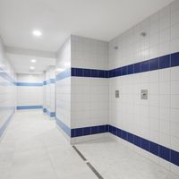 RAKO | Sociální zázemí bazénu Bratislava. Sprcha obložená sérií COLOR TWO ve formátu 20 x 20 cm v bílé a tmavě modré barvě. Na zemi mozaika ze série Cemento ve světle šedé barvě.