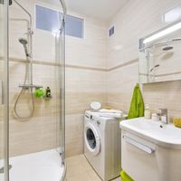 RAKO | Koupelna z lesklých obkladů v odstínech béžové barvy s imitací travertinu a jemným žilkováním. Doplněno o listelu a mozaiku.