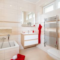 RAKO | Koupelna z lesklých obkladů v odstínech béžové barvy s imitací travertinu a jemným žilkováním. Doplněno o listelu a mozaiku.