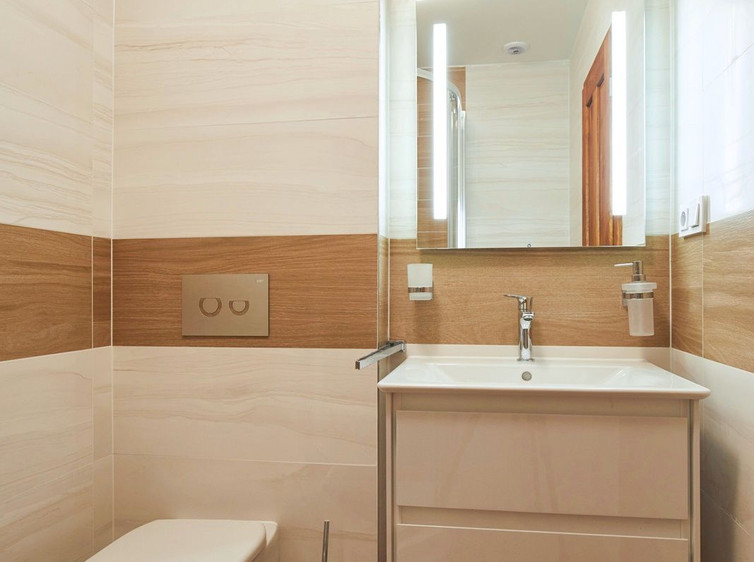 RAKO | Koupelna v bílé barvě s imitací mramoru. Doplněna o dlažbu ze série Board s imitací dřeva v hnědé barvě.