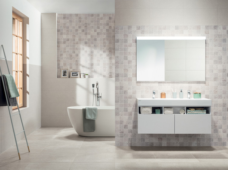 RAKO | Koupelna z obkladů s imitací teraco v odstínu světle šedé v kombinaci s šedou falešnou mozaikou. Na podlaze dlažba v odstínu slonové kosti.