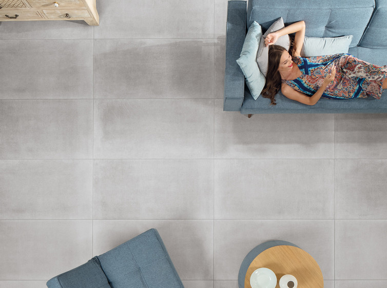 RAKO | Obývací pokoj v industriálním stylu v imitaci betonu s dlažbou na zdi i na zemi ve velkém formátu 60 x 120 cm v šedé barvě.