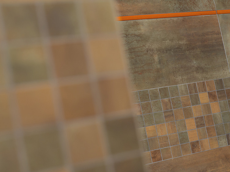 RAKO | Obklady a mozaika v měděné barvě s imitací kovu. Jako doplněk oranžová listela.
