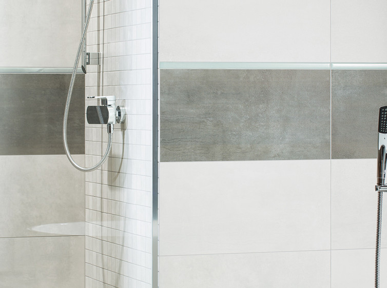 RAKO | Koupelna vytvořená ze světle šedé a tmavě šedé barvy s imitací kovu. Doplněno a světle modrou listelu. 