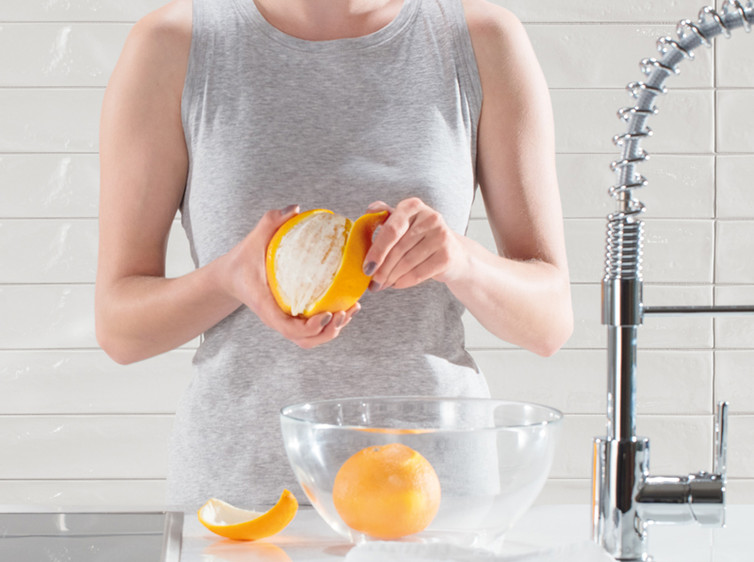 RAKO | Kromě slečny loupající pomeranč jsou zde vidět bílé obklady s reliéfem a vysokým leskem ve tvaru lícové cihly.