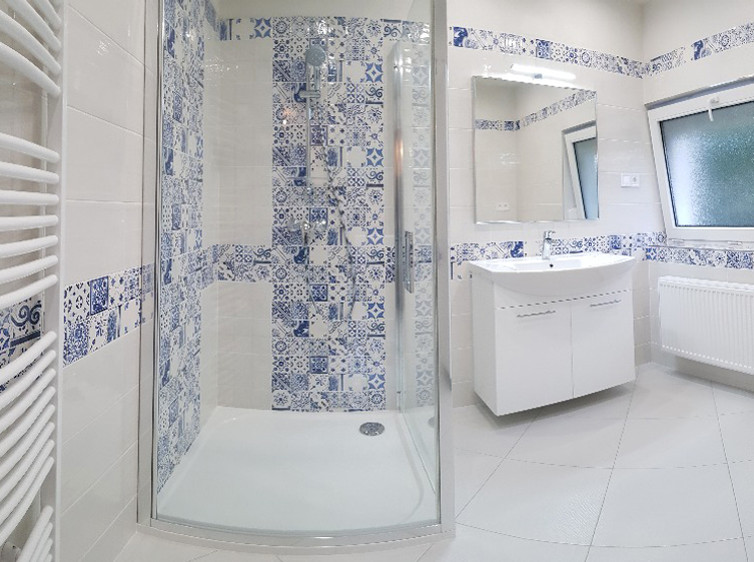 RAKO |Koupelna s lehce taženým stěrkovaným reliéfem v bílé barvě. Majolikový dekor s modré barvě.