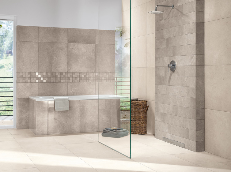 RAKO | Koupelna vytvořená z dlaždic s imitací kamene v béžovošedém odstínu (na zdi) a béžovém (na zemi). Doplněno o béžovošedou mozaiku.