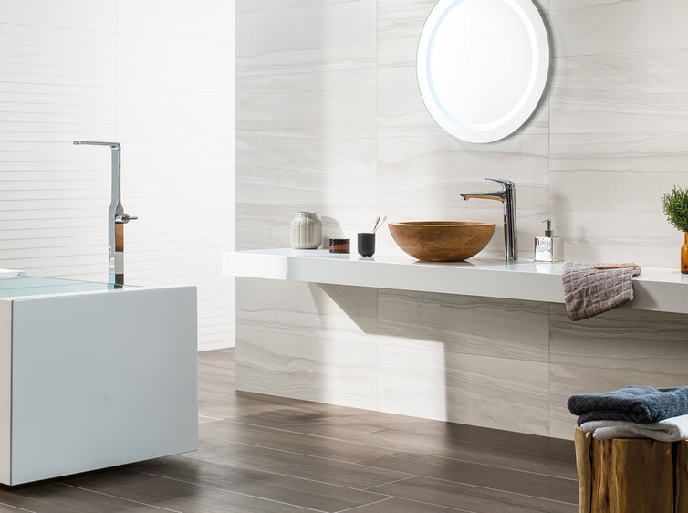 RAKO | Koupelna s imitací mramoru v bílé a světle šedé barvě. Na zemi dlažba ze série Board s imitací dřeva v tmavě hnědé barvě.