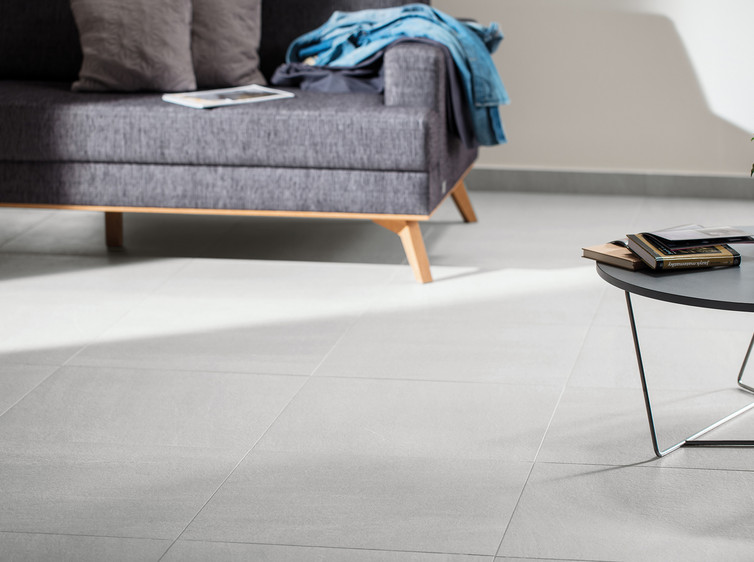 RAKO | Dlažba ve velkém formátu 40 x 80 cm v šedé barvě s imitací kamene využitá jako podlaha do obývacího pokoje.